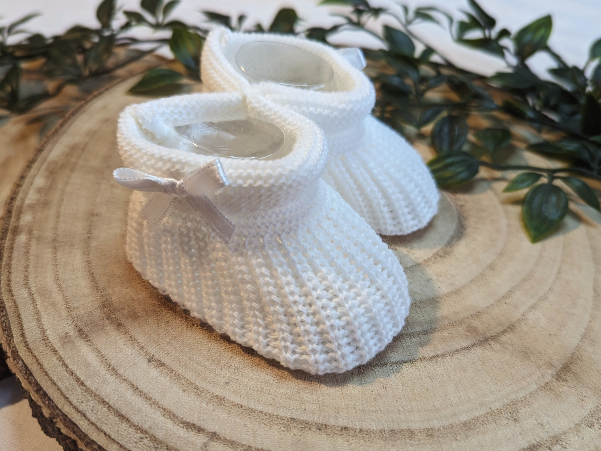 Unisex Newborn Clothes - Baby booties with a white coloured knitted design, featuring a small bow on the side. (Side Angle)